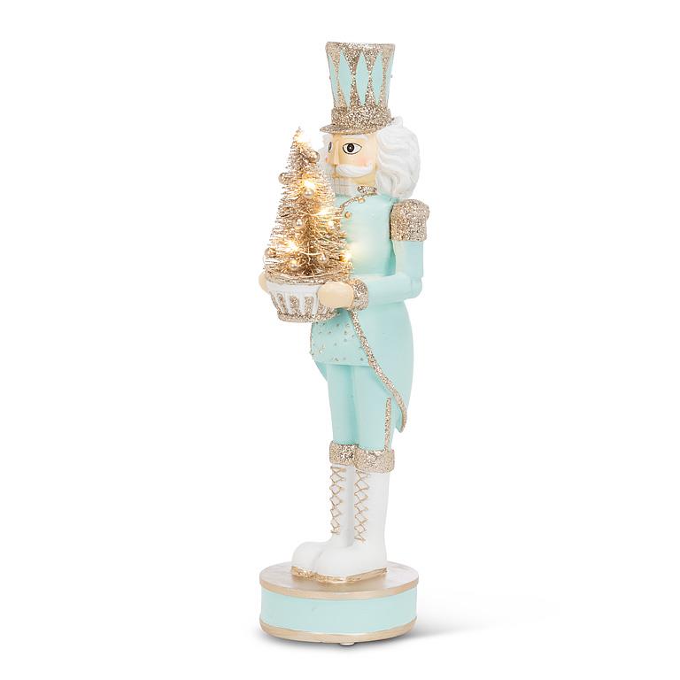 Decorative nutcracker figure holding a lit tree on a white background